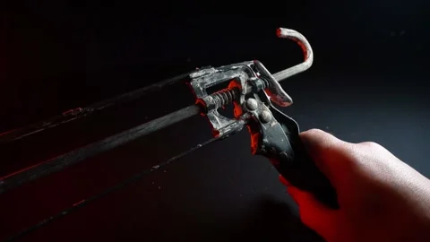 Assembly gun for sealants for construction work in red light Stock Footage 302340409