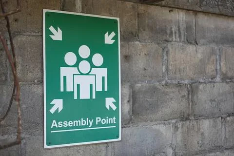 Assembly point sign on brick wall for safety and emergency Stock Photos