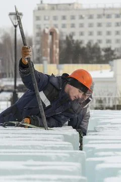 An assembly worker tries to push the ice slabs apart with a crowbar 스톡 사진