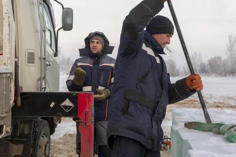 An assembly worker tries to push the ice slabs apart with a crowbar 스톡 사진