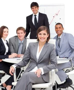 Assertive female executive sitting in front of her team Stock Photos
