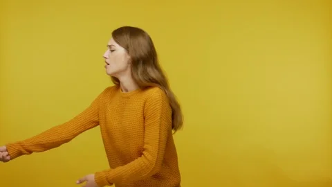 Assertive girl with long hair in pullover pulling invisible rope, dragging heavy Stock Footage 123501636