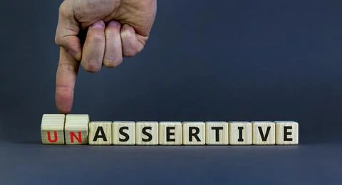 Assertive or unassertive symbol. Businessman turns wooden cubes and changes c Stock Photos