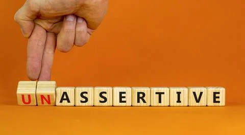 Assertive or unassertive symbol. Businessman turns wooden cubes and changes c Stock Photos