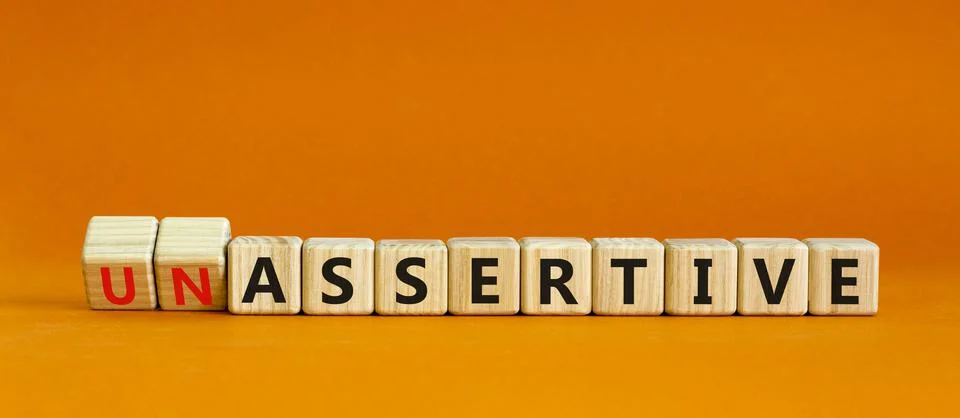 Assertive or unassertive symbol. Turned wooden cubes and changed concept word Stock Photos