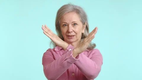 Assertive Senior Woman Making a Stop Gesture with Crossed Arms, Pink Shirt, Teal 스톡 동영상 265872907