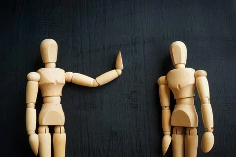 Assertiveness and confidence concept. Two wooden figurines on the dark surface. Stock Photos