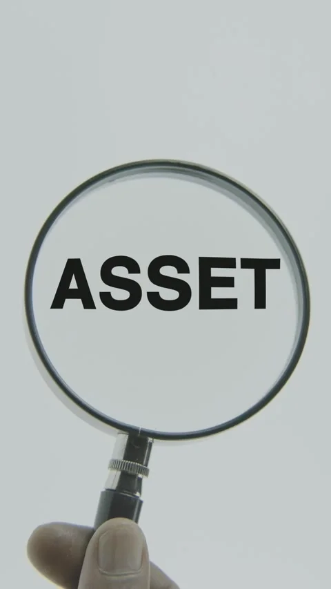 Asset text or word highlighted by a magnifying glass in a hand on a white Stock Footage 303408746