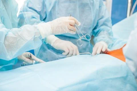 Assistant adds surgeon instruments during surgery, close up of hands in glove Stock Photos
