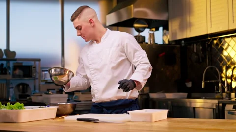 Assistant chef in the kitchen in white jacket cuts beets in his hands over the Stock Footage 273548991