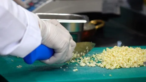 Assistant cook is chopping garlic cloves Stock Footage 99254031