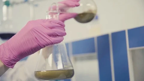 Assistant in gloves pours gold liquid into flask closeup Stock Footage 117682971