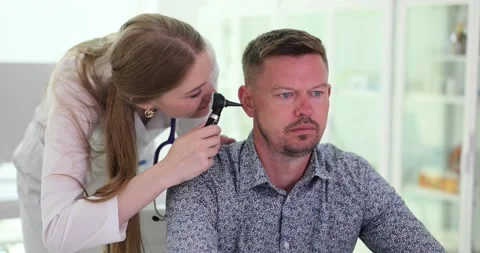 Assistant looking into patient ear inner canal with otoscope Stock Footage 252208154