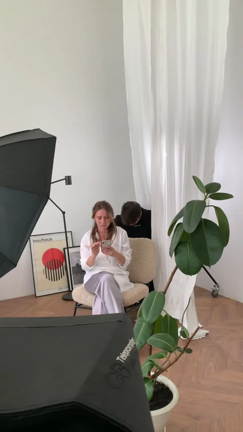 Assistant makes adjustments of equipment as actress browses phone Stock Footage 303065844