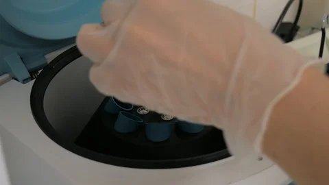 Assistant puts blood sample tubes with specimens into centrifuge machine Stock Footage 121667703