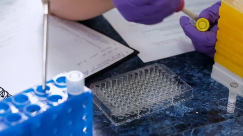 Assistant puts liquid samples into deep well plate in lab Stock Footage 182542030