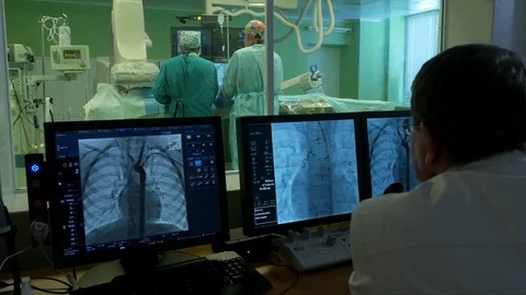 Assistant surgeon controls the progress of surgery on the screen in control room Stock Footage 72693954