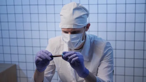 Assistant in uniform looks at blood sample with coronavirus Stock Footage 124892760