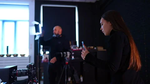 Assistant using smartphone for social media content during filming. Woman 動画素材 334812976