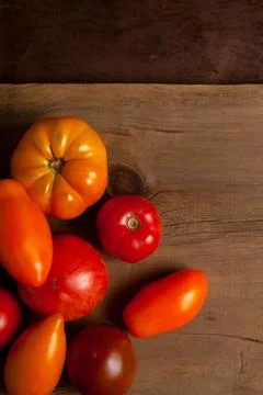 Assort of different shape and color tomatoes on wooden background with red .. Stock Photos