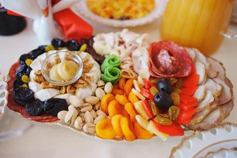 Assorted appetizers on the table is served with classic white and gold dishes. Stock Photos
