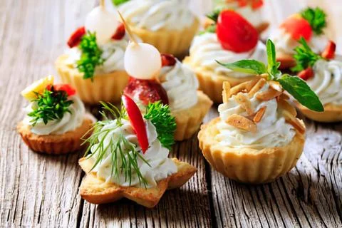 Assorted appetizers on wooden table with garnish Stock Photos