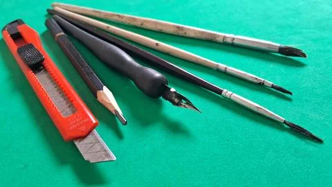 Assorted artistic drawing tools arranged neatly on a vibrant green surface 스톡 사진
