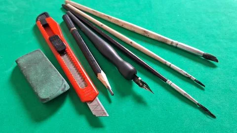 Assorted artistic drawing tools arranged neatly on a vibrant green surface 스톡 사진