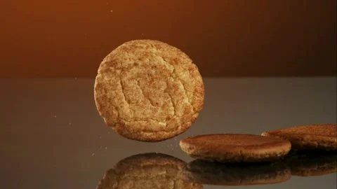 Assorted baked cookies falling and stacking on reflective surface Stock Footage 327576944