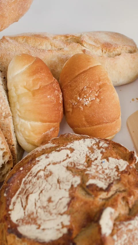Assorted Bakery Breads with Hand Spreading Butter on Sourdough Slice Stock Footage 337519473