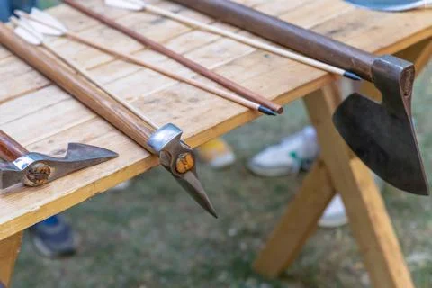 Assorted battle ax and arrow weapon set on a wooden table Stock Photos