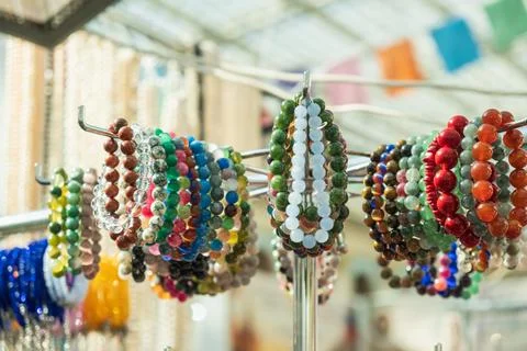Assorted beaded bracelets rest on chrome display rack, each loop packed with Фото