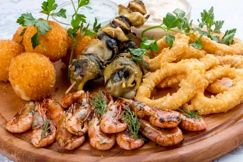 Assorted beer snacks. Cheese balls, mussels grill, shrimp, squid rings. Stock Photos