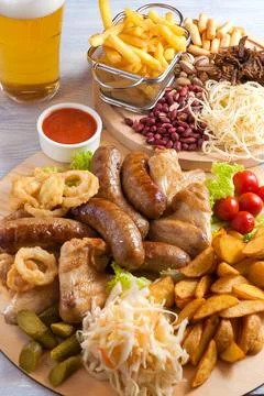 Assorted beer snacks: chicken wings, grilled sausages, potatoes, nuts, cheese Stock Photos