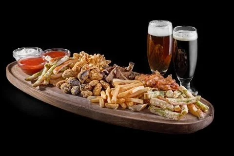 Assorted beer snacks. crackers, fried pieces of meat, french fries, chicken w Stock Photos