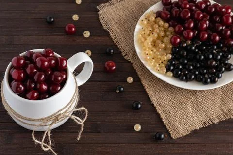 Assorted berries of cherries, white and black currants are on a wooden table. Stock Photos