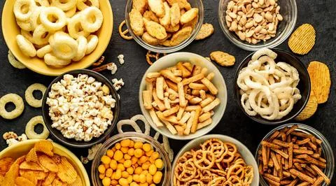 Assorted bowls of snacks and chips on black table Stock Photos