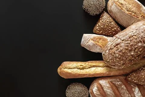 Assorted bread rolls and breadsticks on black background Foto stock