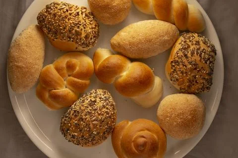 Assorted bread rolls on round white plate, overhead view on background Stock Photos