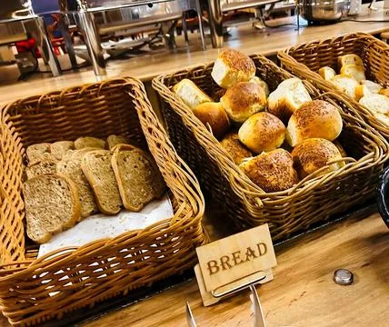 Assorted Breads in Wicker Baskets on a Wooden Table Фото