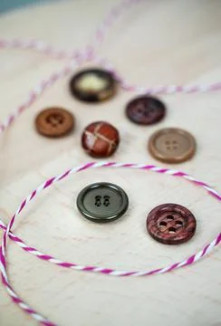 Assorted buttons and striped string on light wood Stock Photos