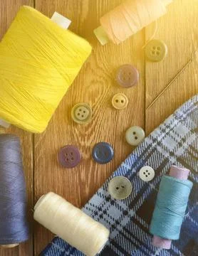 Assorted buttons and thread spools on wooden surface Foto stock