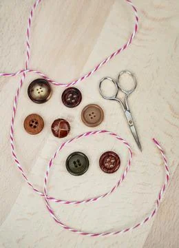 Assorted buttons, striped string and scissors on light wood background 库存照片