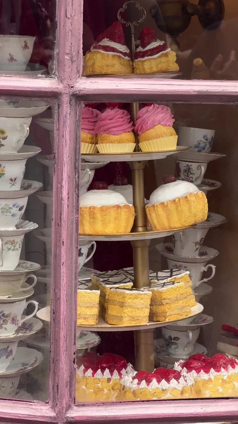 Assorted cakes and muffins displayed on a tiered stand in a shop window Video stock 338342167