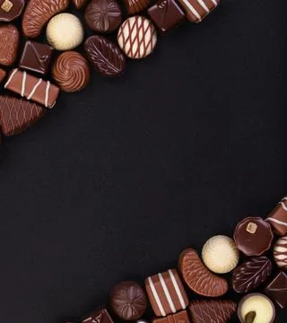 Assorted candy of white and dark chocolate on black table background with emp Stock Photos