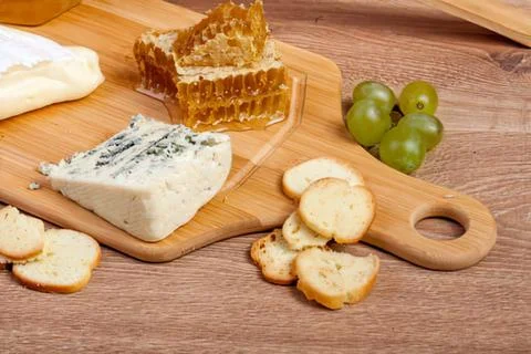 Assorted cheese, bread, and grapes on wooden boards 스톡 사진