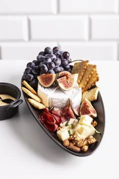 Assorted cheese, prosciutto, nuts, snacks and fruits Stock Photos