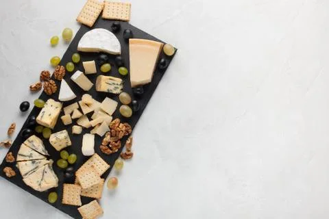 Assorted cheeses with white grapes, walnuts, crackers and on a stone Board. F Stock Photos