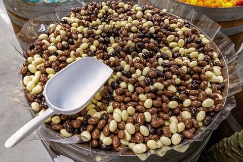 Assorted chocolate-covered nuts in bulk bin. Large wooden barrel filled with Stock Photos