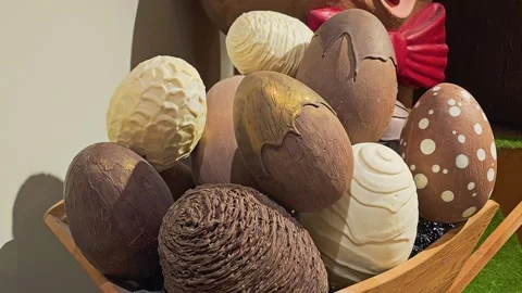 Assorted chocolate Easter eggs with detailed patterns and textures in a wooden Stock Footage 335220602